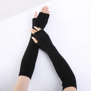 Detail of black long fingerless knitted gloves featuring ribbed texture and arm warmer length