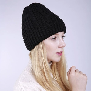 Close-up of black cable knit beanie with folded cuff shown on model for winter warmth