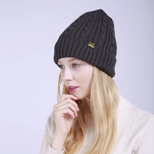 Detailed close-up of dark grey cable knit beanie featuring a yellow brand label