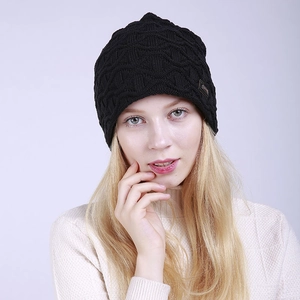 Nahaufnahme einer schwarzen Strickmütze mit Rautenmuster und einem kleinen Lederaufnäher