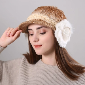Detail of brown and khaki knit winter hat with fuzzy white faux fur earflaps and embroidery