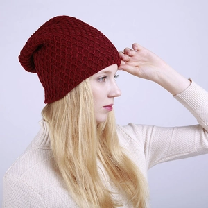 Primer plano de un gorro de punto color burdeos con textura de panal usado por una modelo
