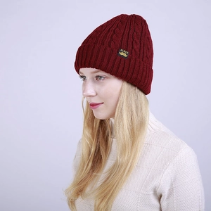 Detailed knit texture of burgundy beanie with a side label on a winter sweater