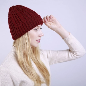Detail of burgundy cable knit winter beanie featuring thick ribbed cuff and warm texture