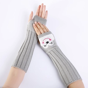 Detail van grijze gebreide armwarmers met schattig cartoonborduurwerk en ribgebreide textuur