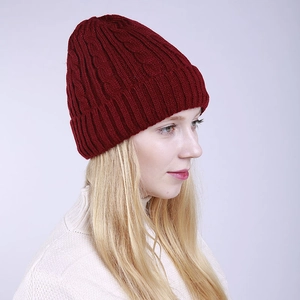 Close-up of deep red cable knit beanie with thick rolled cuff and winter texture