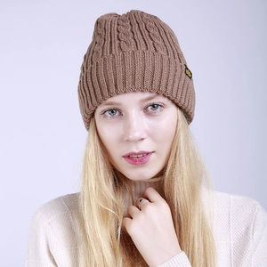 Detail of brown cable-knit beanie with a small yellow bee logo patch and ribbed edge