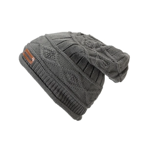 Detailed view of dark grey cable knit texture and brown leather patch on winter beanie