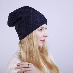 Detalle del gorro de punto azul marino con diseño de rombos en una modelo con suéter