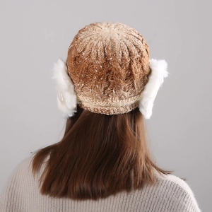 Detail of knitted winter hat featuring faux fur earflaps and mixed beige textured weave