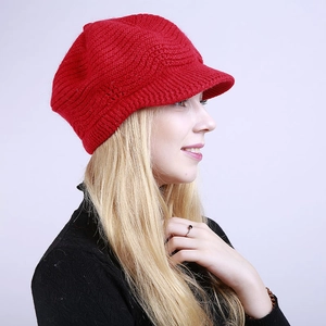 Detail view of red knitted visor beanie with warm wave pattern and thick yarn texture