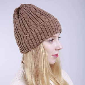 Close-up of brown winter knit beanie with classic cable pattern and warm ribbed cuff