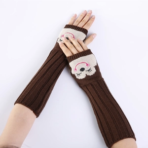 Detail van bruine gebreide armwarmers met een schattige geborduurde apengezicht patch