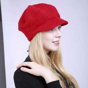 Detailed close-up of the red knitted newsboy hat showing thick wool wave texture