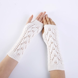 Close-up of white knit arm warmers with hollow diamond leaf pattern and fingerless design