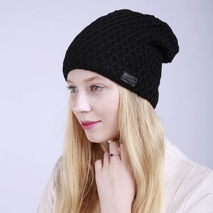 Detalle de gorro de punto negro con diseño de nido de abeja, parche de cuero y forro polar