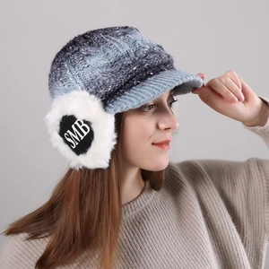 Detail of winter cable knit hat featuring faux fur earflaps with black heart and SMB logo
