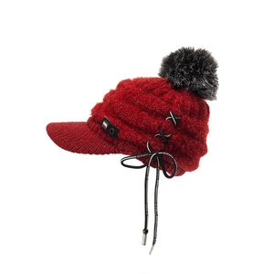 Nahaufnahme der dunkelroten Strickmütze mit Kunstfell-Pompon und bedrucktem Band