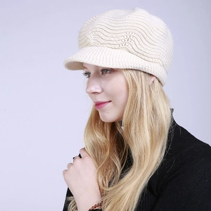 Detail of cream white knit peak cap showing wavy textured patterns and short brim