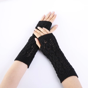 Detail of black cable knit fingerless gloves showing intricate cutout patterns on arm