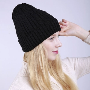 Close-up of black cable-knit beanie with folded brim on model for winter warmth