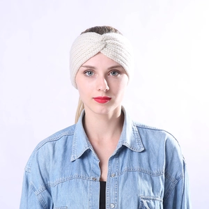 Gros plan d'un bandeau en maille crème avec un nœud torsadé porté par un mannequin femme