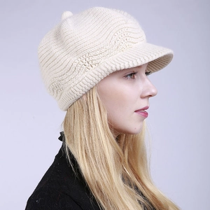 Side view of beige knitted newsboy cap with brim showing soft texture and warm winter style