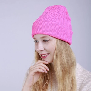 Detail of bright pink ribbed knit beanie with turn-up cuff worn by a model