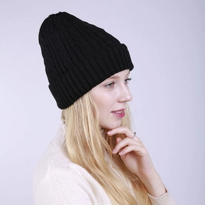 Side view of black cable knit beanie featuring a thick cuffed edge on female model
