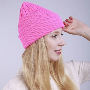 Close-up of bright neon pink knitted beanie showing ribbed texture and folded cuff detail