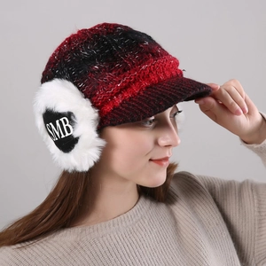 Detail view of winter knitted visor hat with red-black plaid pattern and white faux fur earflaps