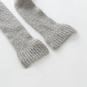 Detail shot of grey knitted wool leg warmers showing thick ribbed texture on white background