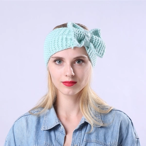 Primo piano di una fascia in maglia verde menta con un grande fiocco su una modella