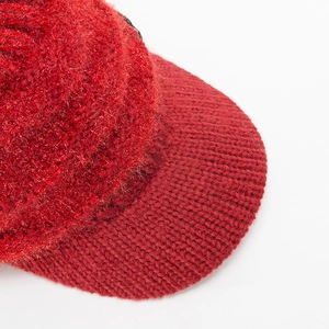 Detailansicht des roten Strickstoffs und der flauschigen Kunstfellstruktur einer Wintermütze