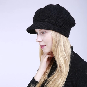 Detail of black knitted beret showing thick wave-textured fabric and short brim design