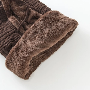 Detailed close-up of chunky cable knit texture and thick brown fleece lining on winter hat