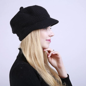 Side view of a black knitted newsboy cap with vertical striped texture on a model