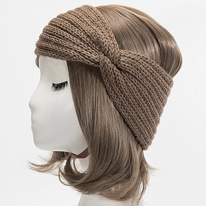 Gros plan d'un bandeau en maille marron montrant la texture torsadée et le design croisé