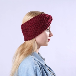 Detail view of burgundy knitted headband on model showing thick ribbed texture and crossover