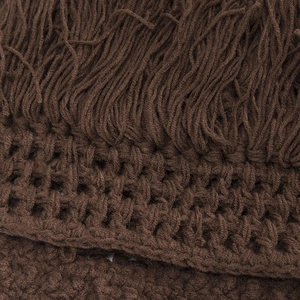 Macro detail of dark brown knit texture and long fringe tassels on a handmade beanie