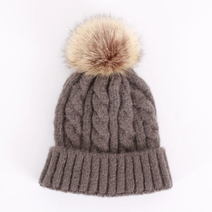 Detailed view of thick cable knit texture and large fluffy pom-pom on dark grey beanie