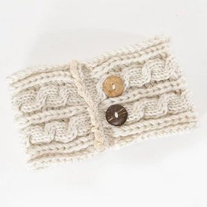 Close-up of cream cable knit ear warmer headband with lace edges and wooden buttons