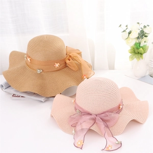 Dettaglio di cappelli di paglia a tesa larga con fiocco floreale e perle