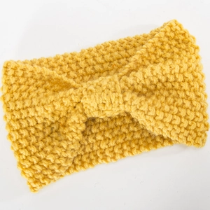 Detail eines gelben Strickstirnbands mit grober Garnstruktur und Schleifendesign in der Mitte