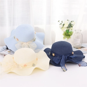 Dettaglio di cappelli di paglia con fiocchi a rete, perle e decorazioni floreali