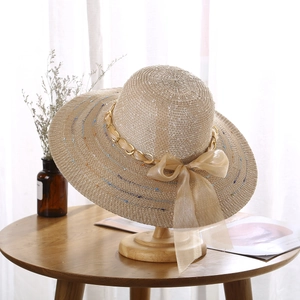 Détail d'un chapeau de paille à large bord avec chaîne et nœud en organza champagne
