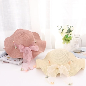 Dettaglio di cappello di paglia con fiocco in organza e decorazioni floreali