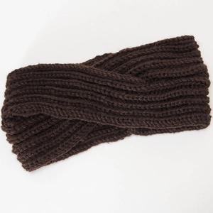 Macro shot of dark brown chunky knit texture and trendy knotted cross design on headband