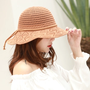 Close-up of brown crochet straw hat with breathable knit pattern and bow detail