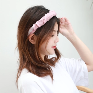 Close-up of pink fabric headband with woven crisscross design and silver thread accents